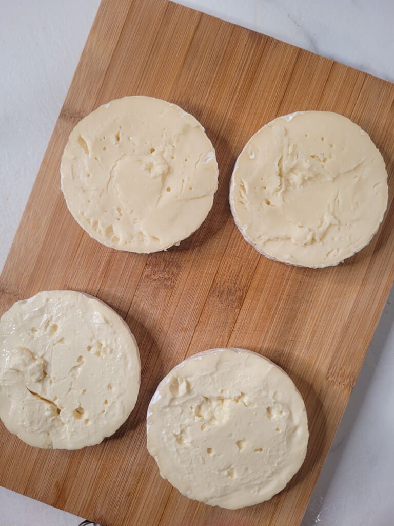 Wheel of cheese sliced in half on wooden board