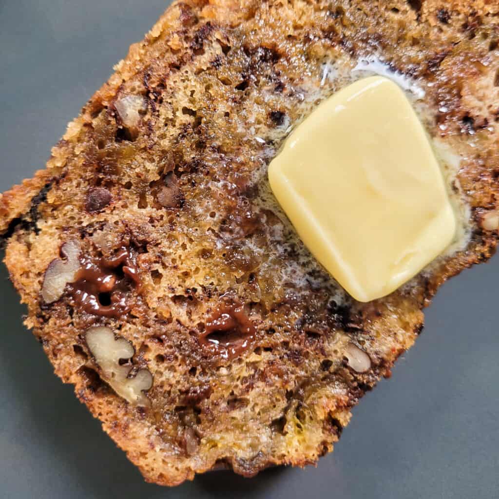 Closeup of banana bread slice with a slice of butter on top