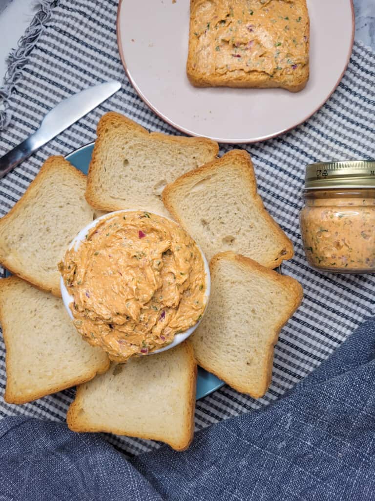Sardine pâté on striped map next to a jar, blue towel, and a plate of bread
