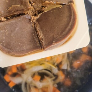 Closeup of Japanese curry blocks above a pot of water with vegetables