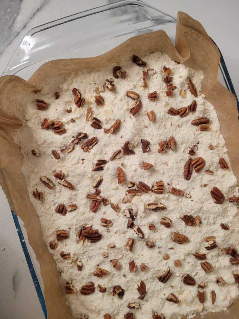 Chopped pecans on top of cake mix in a glass baking dish