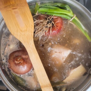 Onions, green onions, and other ingredients boiling in a pot of water