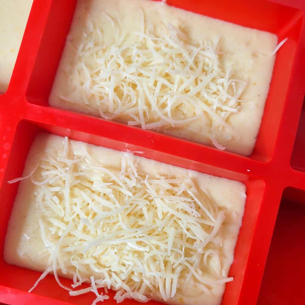 Closeup of shredded cheese on top of batter in mold