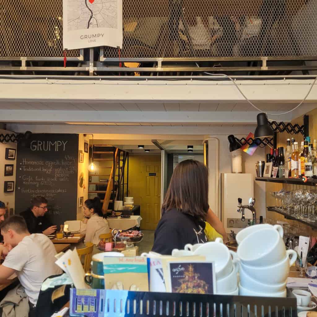 View of inside restaurant with kitchen and diners.