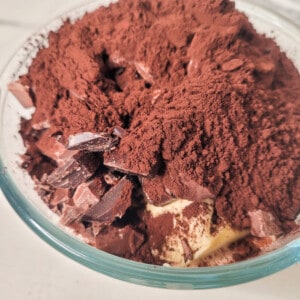 Chopped chocolate, butter, cocoa powder, instant coffee powder in a glass bowl