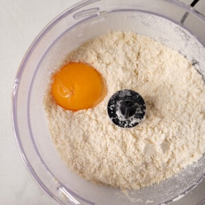 Added egg yolk in a food processor with sandy flour mixture.