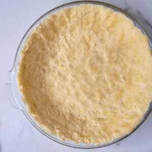 Raw pie dough pressed throughout the inside of a pie pan.