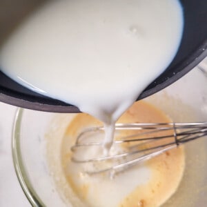 Pour hot milk into raw custard.