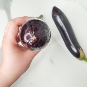 A scored cross at the tip of an eggplant made with a knife