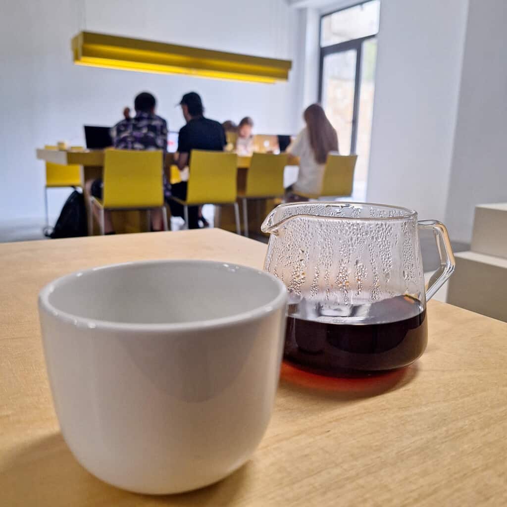 A cup of coffee with people working at a table