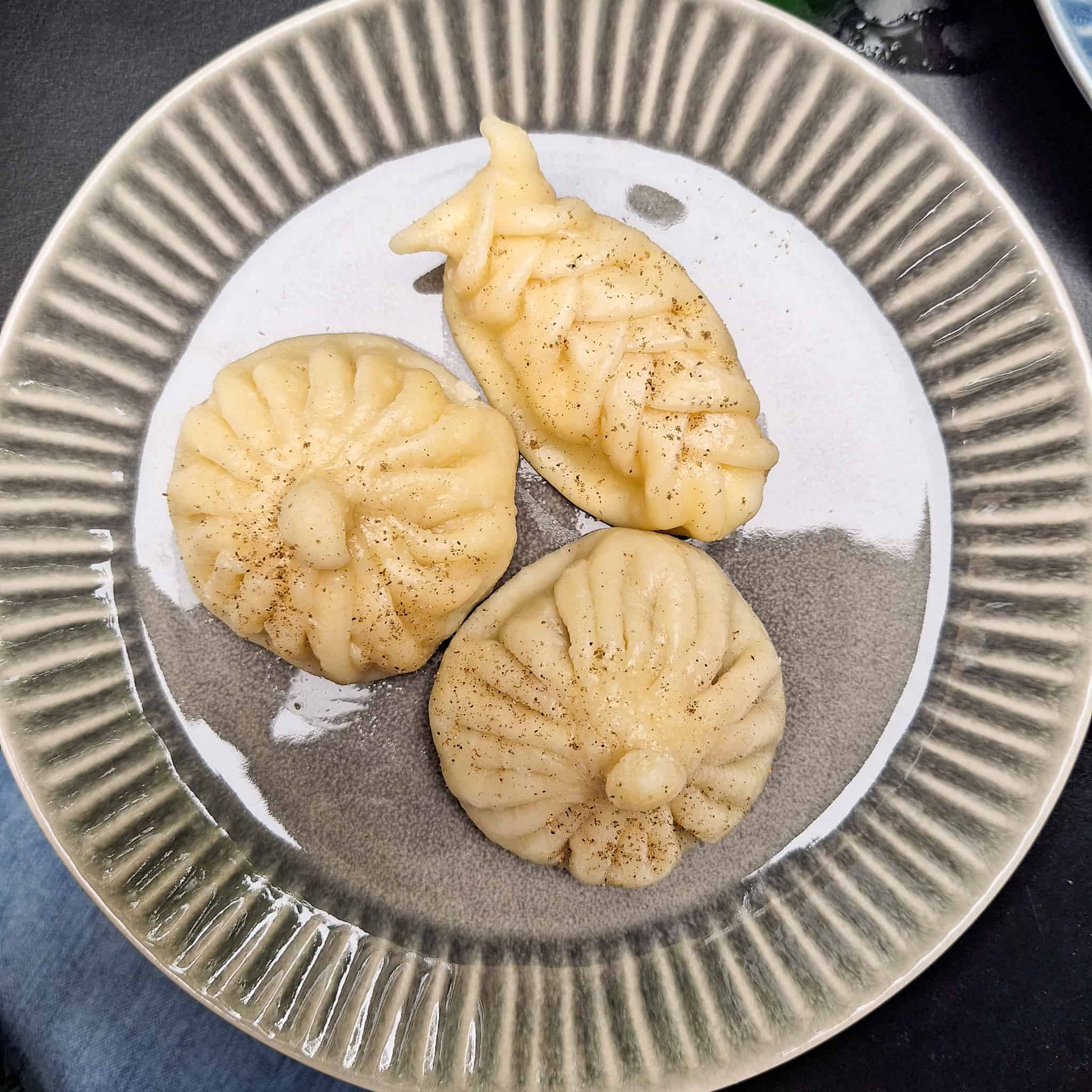 Khinkali, also known as Georgian dumplings, of different shapes on a gray plate