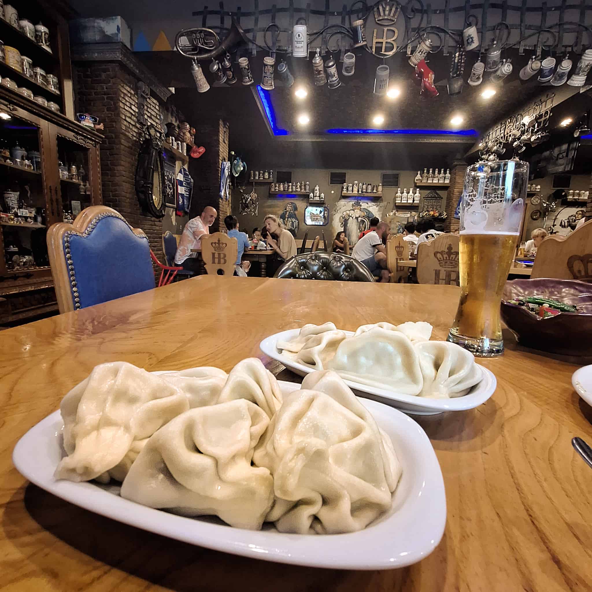 View of the inside of a beer house and Georgian dumplings and beer in the foreground