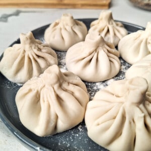 Closeup of several khinkali (Georgian dumplings) on a floured gray plate.