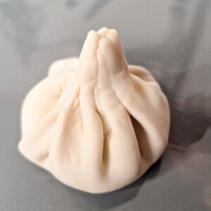 Closed and pleated khinkali on a gray plate.