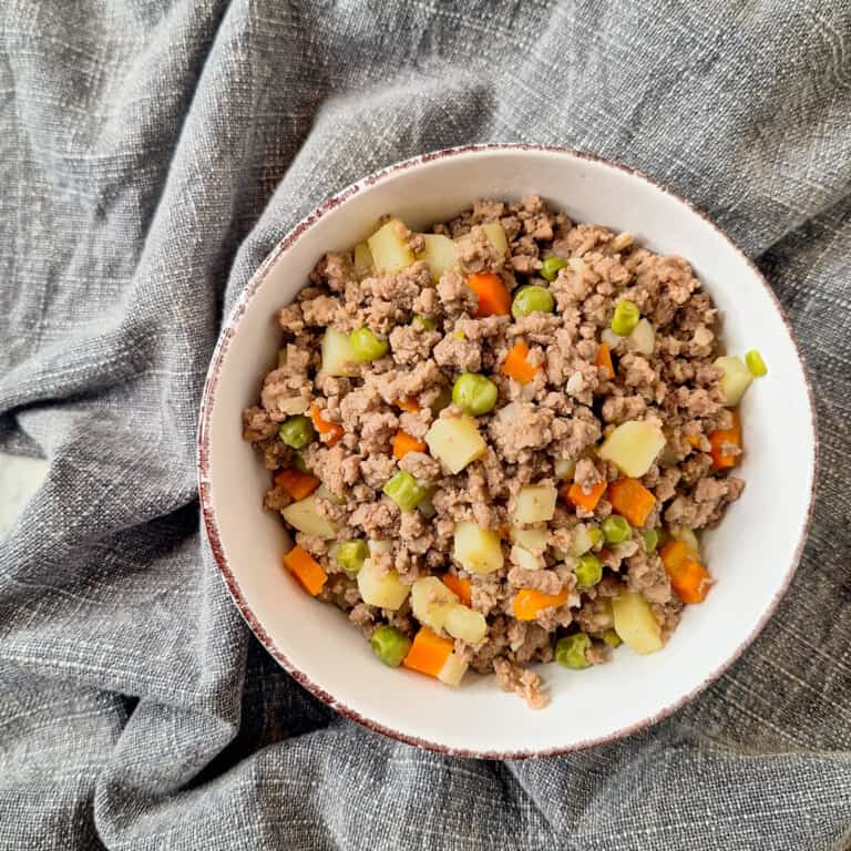 Beef and pork giniling in a white bowl on top of a blue towel