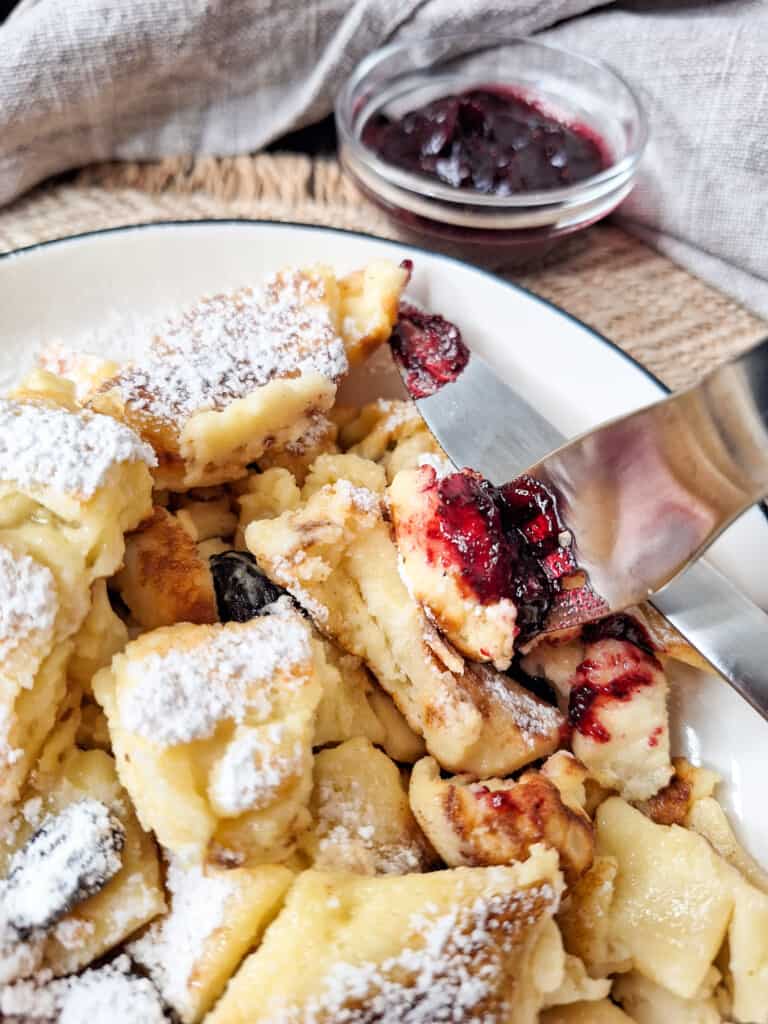 Austrian Kaiserschmarrn or torn pancakes in a white plate with jam