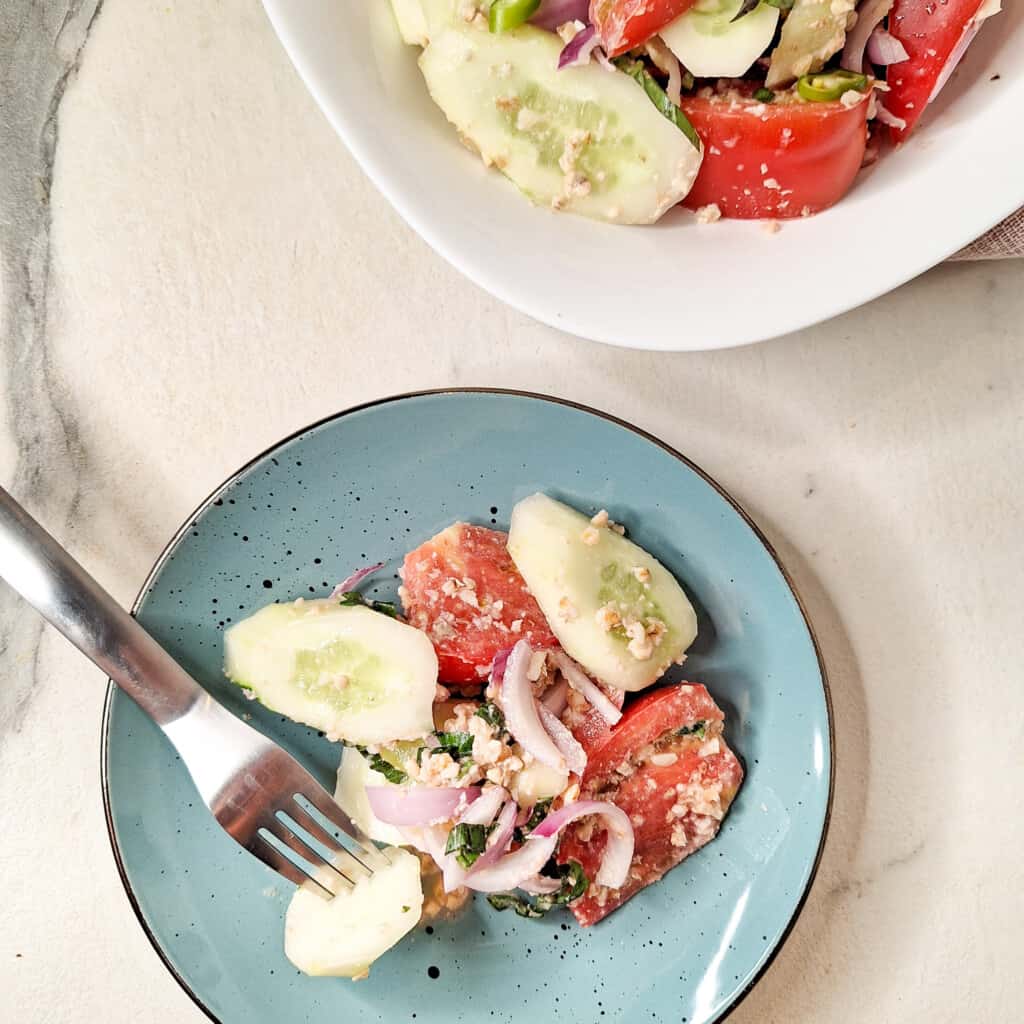 A serving of Georgian cucumber tomato salad in a blue plate