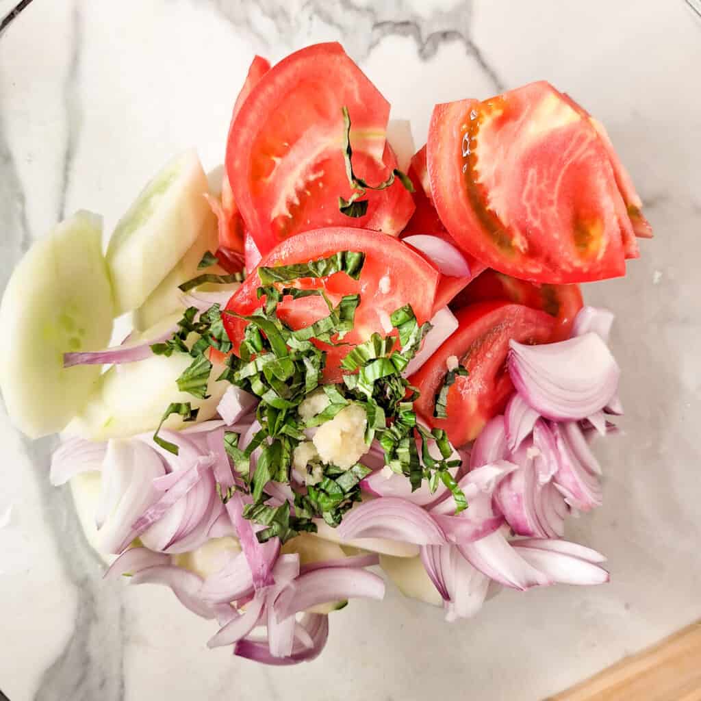 Sliced tomatoes, cucumbers, and onions with grated garlic and sliced basil