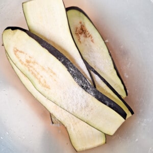 Sliced strips of eggplants with salt in a bowl