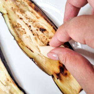 Rubbing a garlic clove along a slice of eggplant