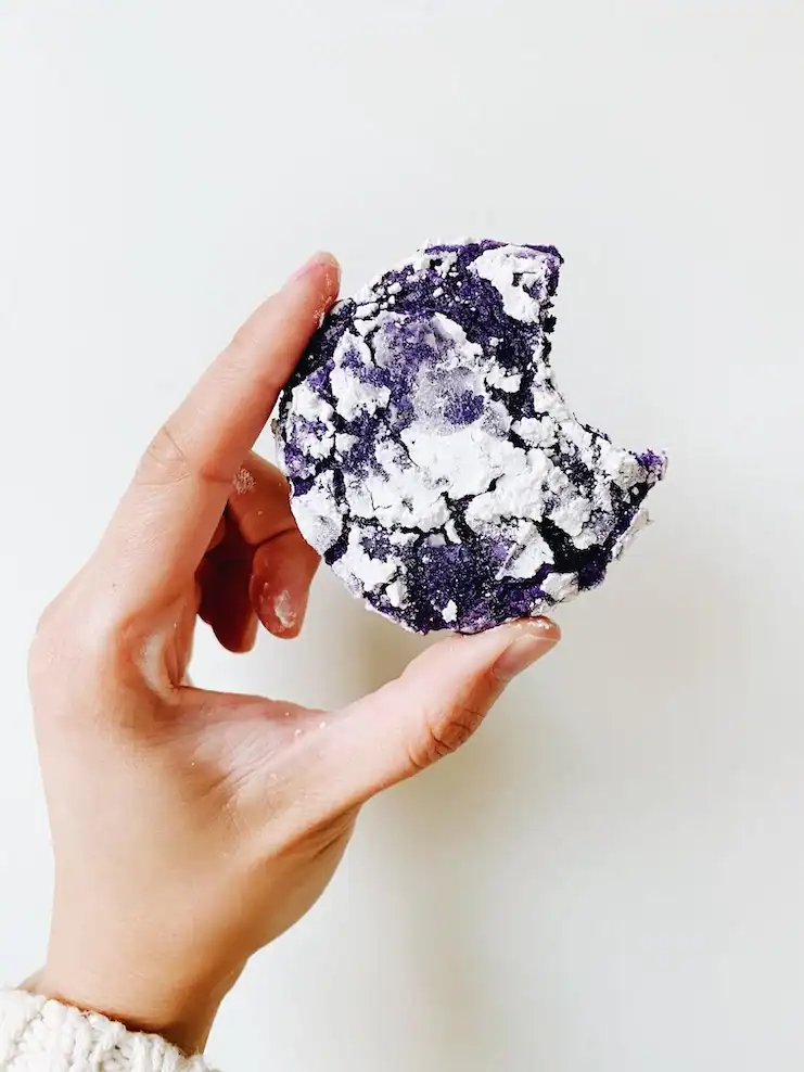 A hand holding a bitten ube crinkle cookie