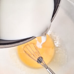 Pour heated milk into bowl of mixed egg yolks and sugar