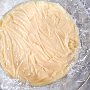 Cooked custard covered by clingwrap in a glass bowl