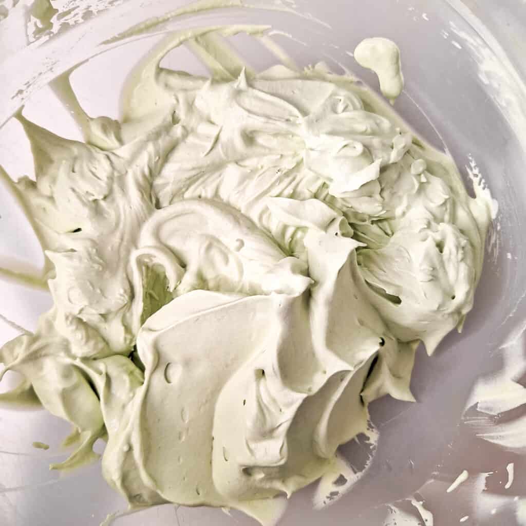 Thickened heavy cream with matcha powder in a plastic bowl