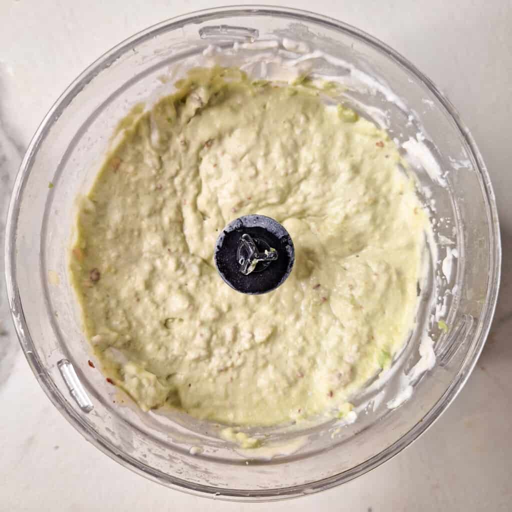 Blended avocado dip ingredients in a food processor.