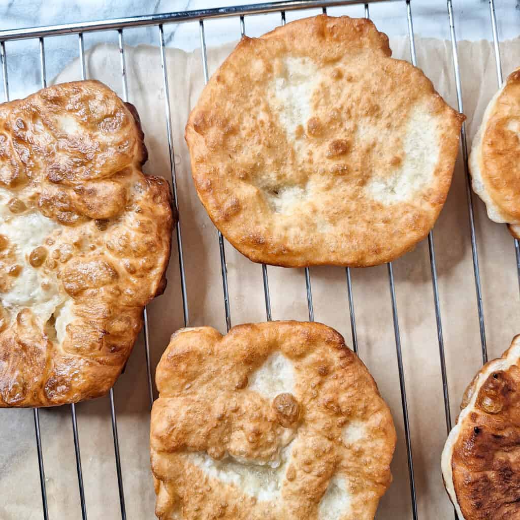Deep fried bread pancakes resting on a wire rack