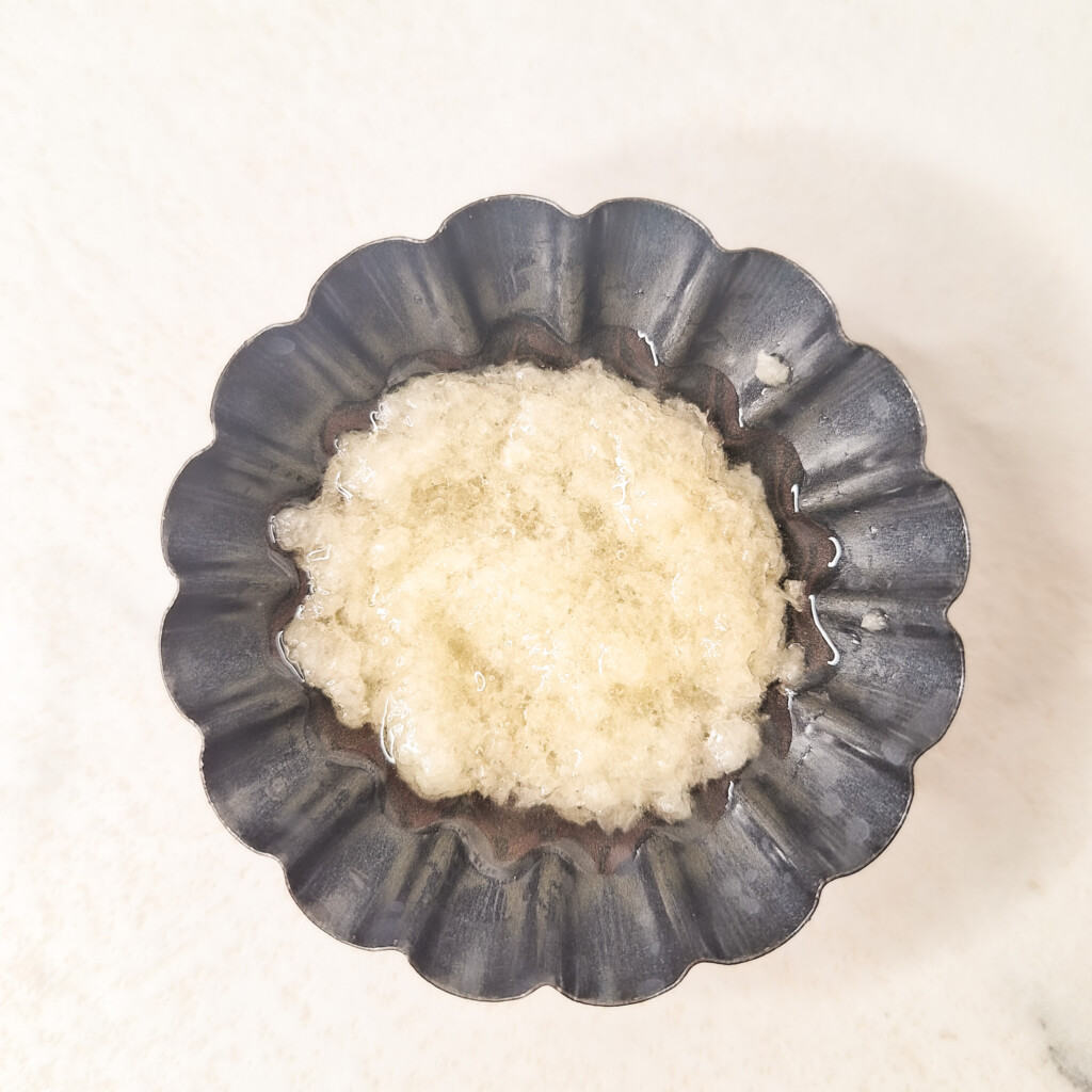 A small silver bowl with minced garlic oil
