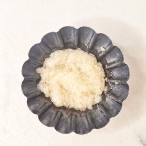 A small silver bowl with minced garlic oil
