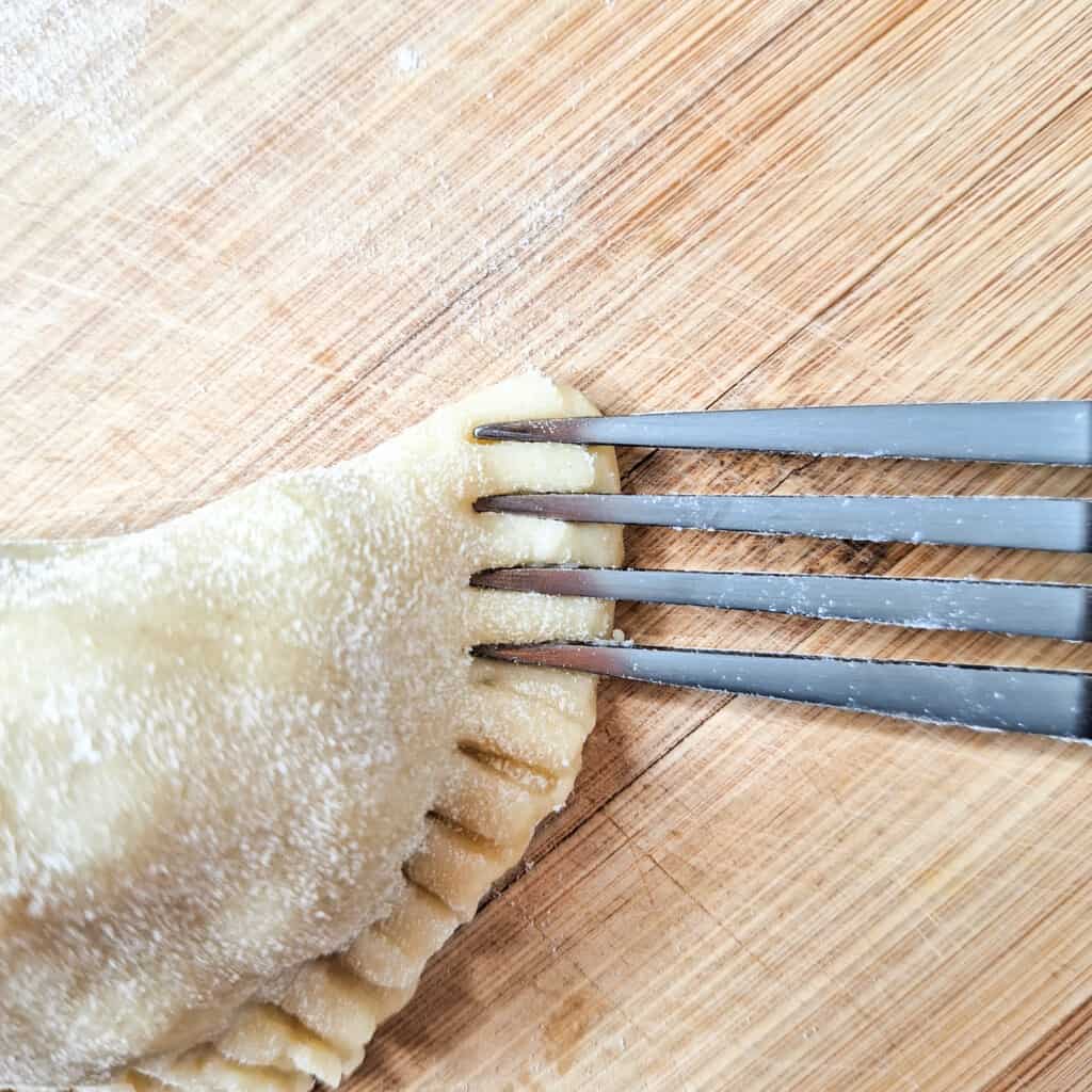 Crimping edges of empanada with the back of a fork