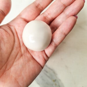 Hand holding a filled sesame ball before rolling in sesame seeds