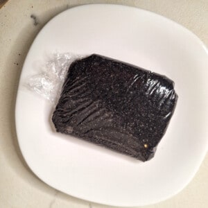 Black sesame paste in clingwrap on a plate
