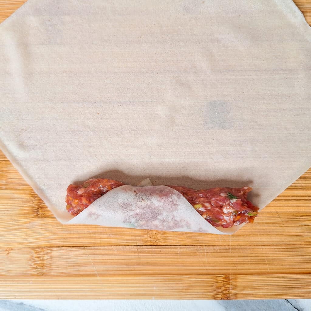 piece of flour wrapper over raw spring roll meat