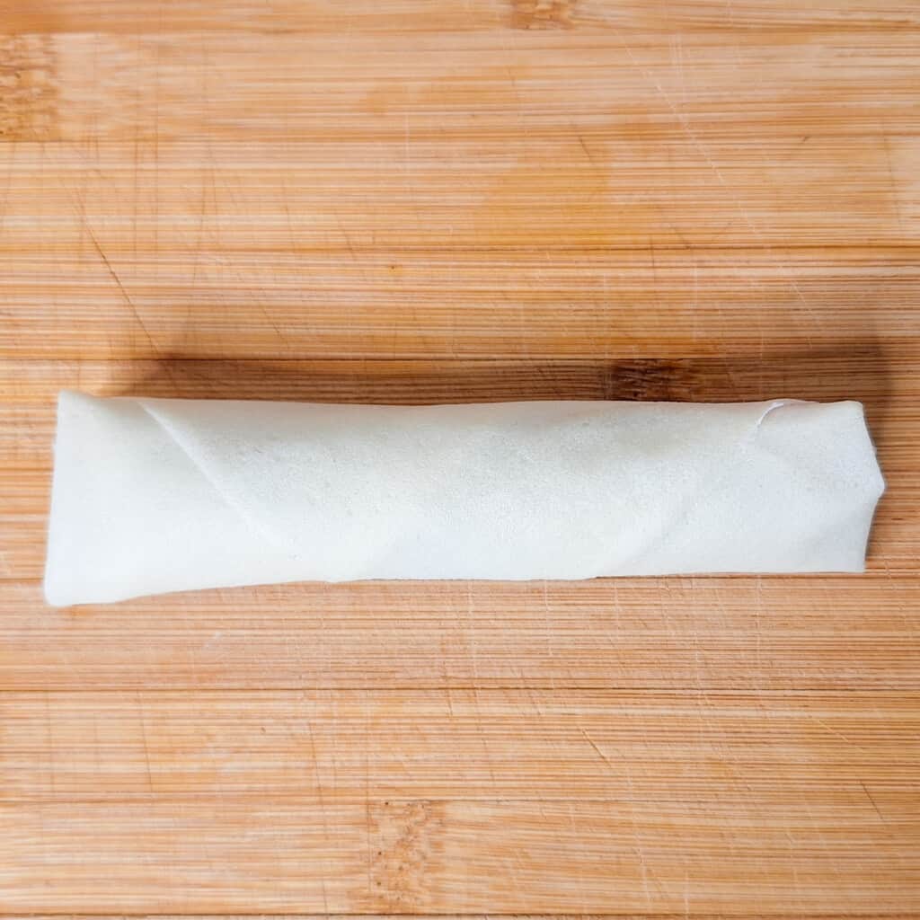 A rolled lumpia on a wooden surface