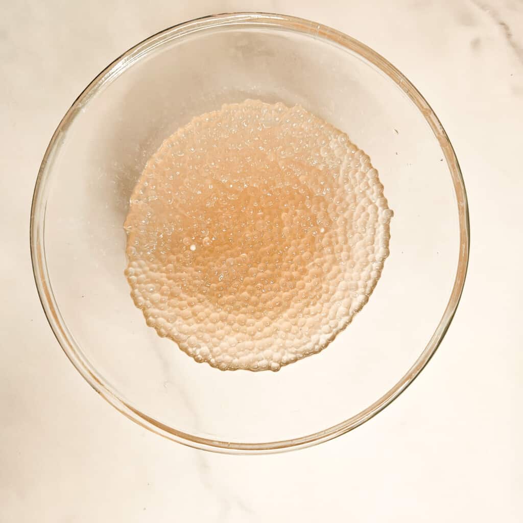 A glass bowl filled with thoroughly cooked sago or tapioca balls