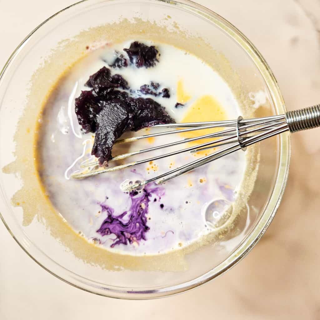 Ingredients for ube tres leches cake in a glass bowl.