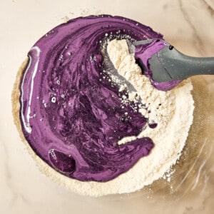 Purple egg yolk mixture with dry ingredients in a bowl.