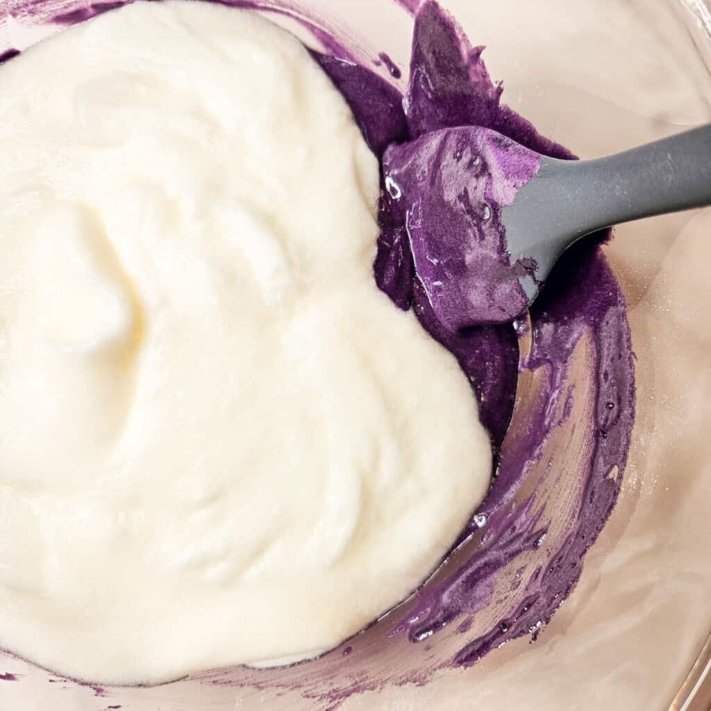 Folding egg whites with other ingredients in a glass bowl.