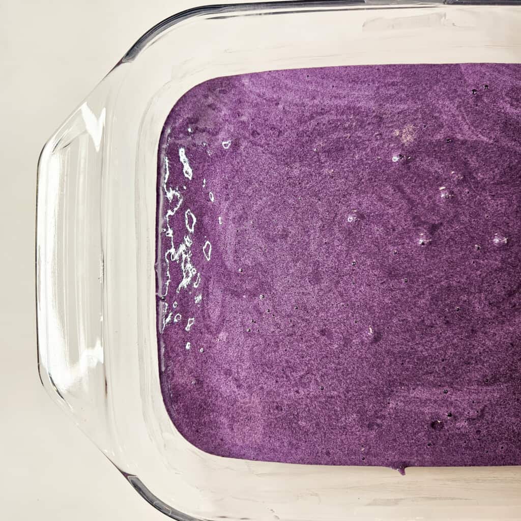 Ube tres leches cake batter in a glass baking dish.
