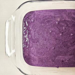 Ube tres leches cake batter in a glass baking dish.