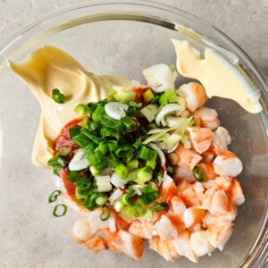 Chopped shrimp in a glass bowl with green onions, Kewpie mayo, and Sriracha