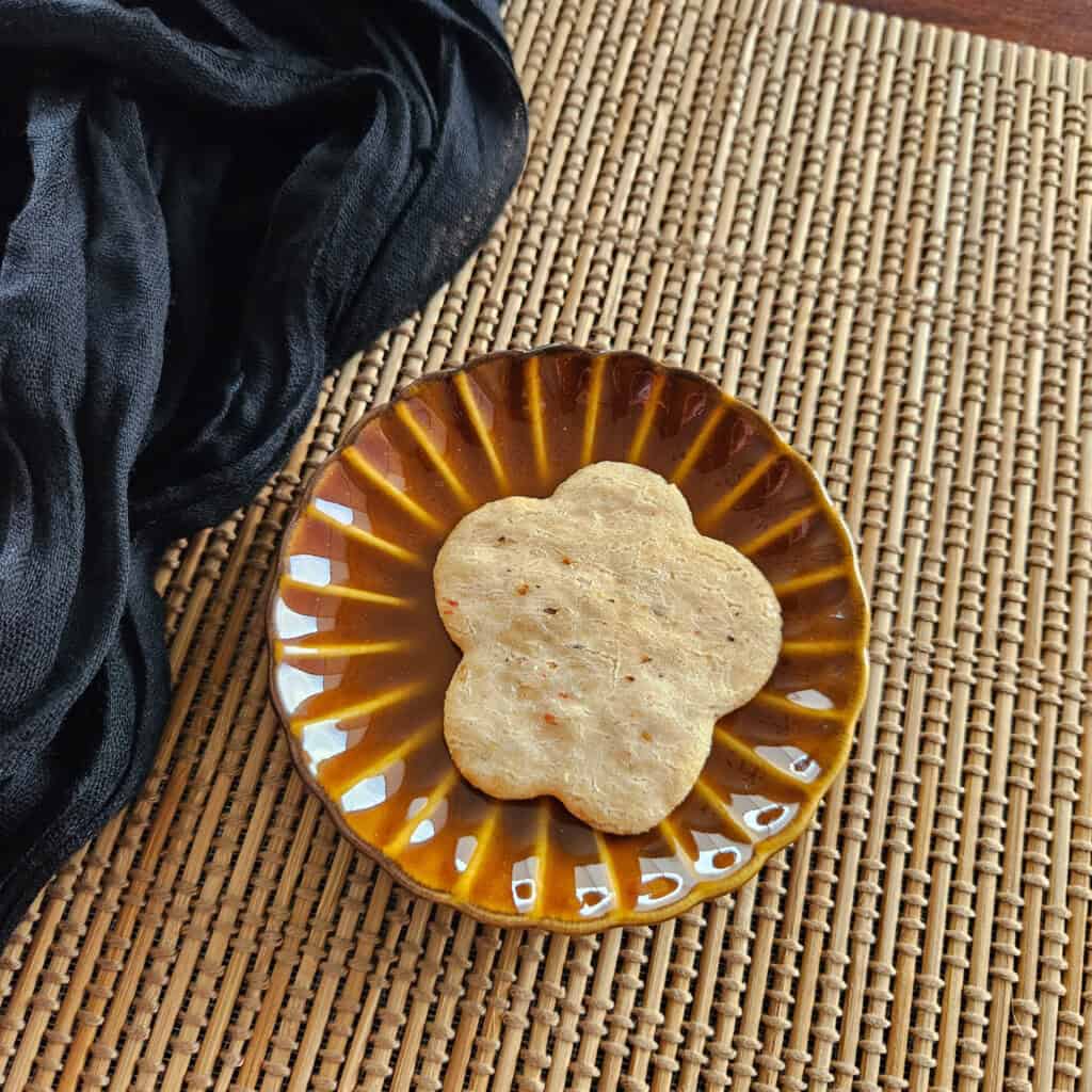 A piece of Japanese shrimp senbei or rice cracker on a brown plate