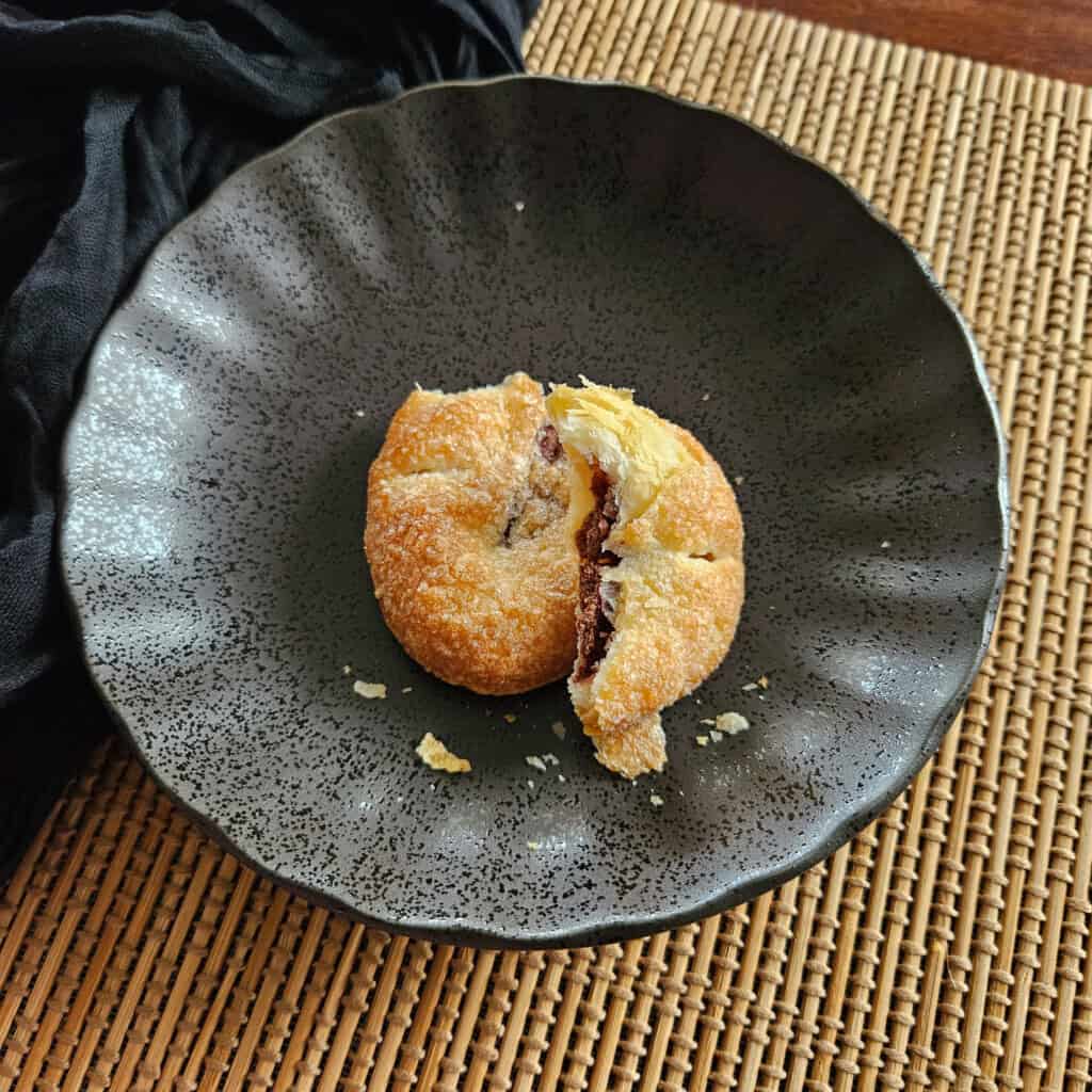 A chocolate pastry broken in half on a dark plate