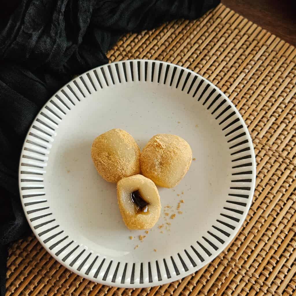 Three pieces of mochi with soybean powder coating and filled with roasted green tea filling